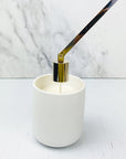 Gold plated candle snuffer being used to put out wick in a white ceramic jar