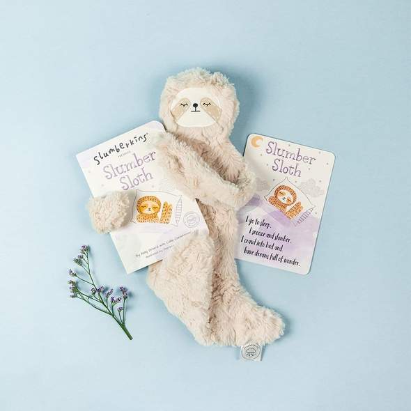 Slumberkins Slumber Sloth stuffed toy with Slumber Sloth hard book. Shown on blue background with floral accent.