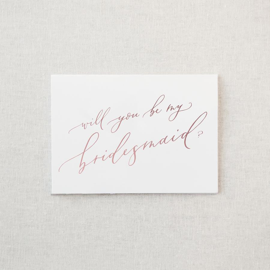 White envelope size card (approx. 3.5&quot; x 5&quot;), reads, &quot;Will you be my bridesmaid?&quot; in rose gold text.