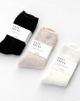 Three pairs of chenille socks. Black, nude, and ivory color options. Each has a white band around the center that reads "Cozy Socks"