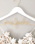 Personalized white hanger with gold hook. Gold wire base shaped into personalized name.