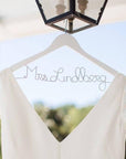 White wooden hanger with silver hook. Silver wire base shaped into personalized name