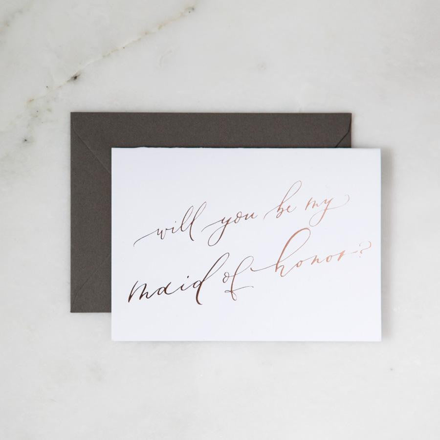 White envelope size card (approx. 3.5&quot; x 5&quot;), reads, &quot;Will you be my maid of honor?&quot; in rose gold text, with slate gray envelope option.