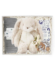 A gray swaddle blanket, a white stuffed bunny, floral bundle, wooden baby rattle, and animal graphic printed box of 'night night body wash' in a gray 'foxblossom' box with ivory paper shread.